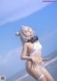 A woman in a white bikini standing on a beach.