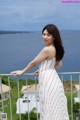 A woman in a white and orange dress standing on a balcony.