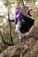 A woman with purple hair holding a bow and arrow.